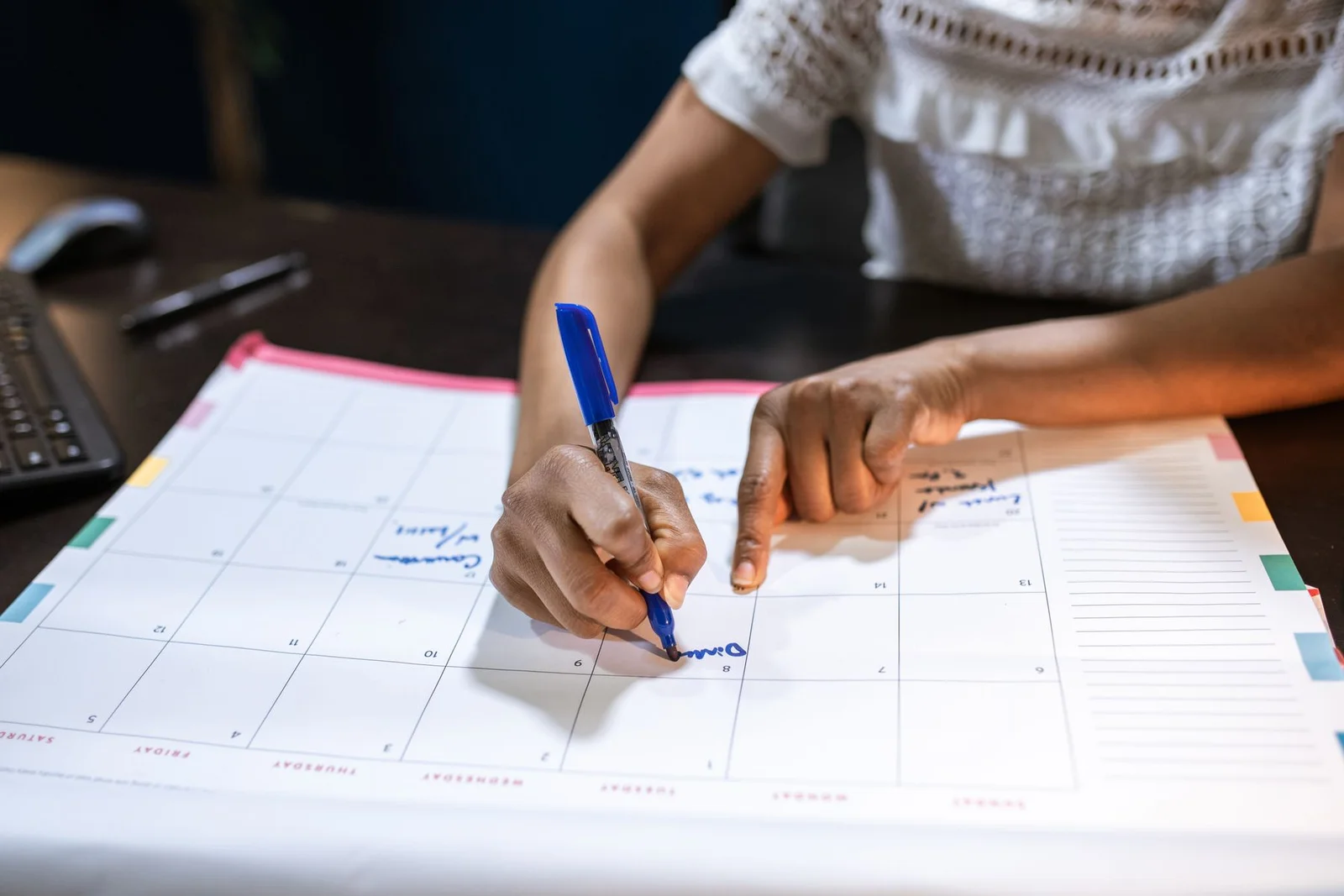 Person marking dates on a paper calendar