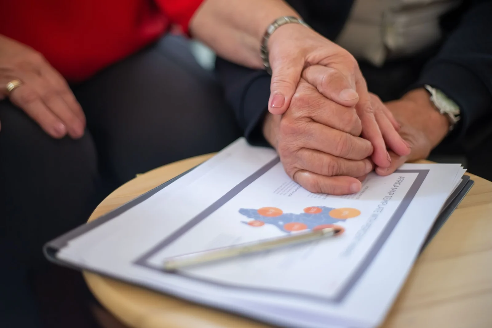 Two people holding hands over paperwork