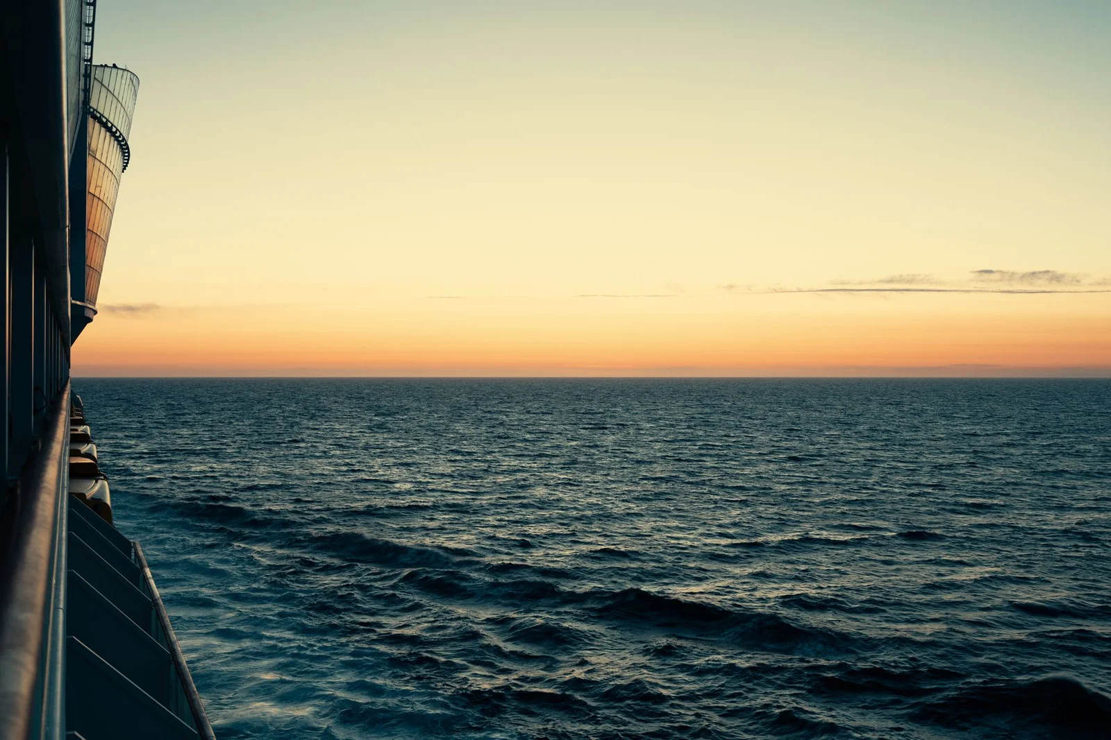 Ocean horizon viewed beside a passenger ship at sunset